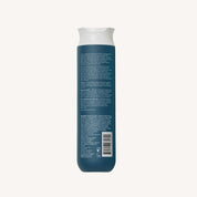 A blue bottle of Clarifying Detox Shampoo with a white cap is shown from the back, featuring product information and a barcode on the label. This formula removes buildup and is ideal for hard water.